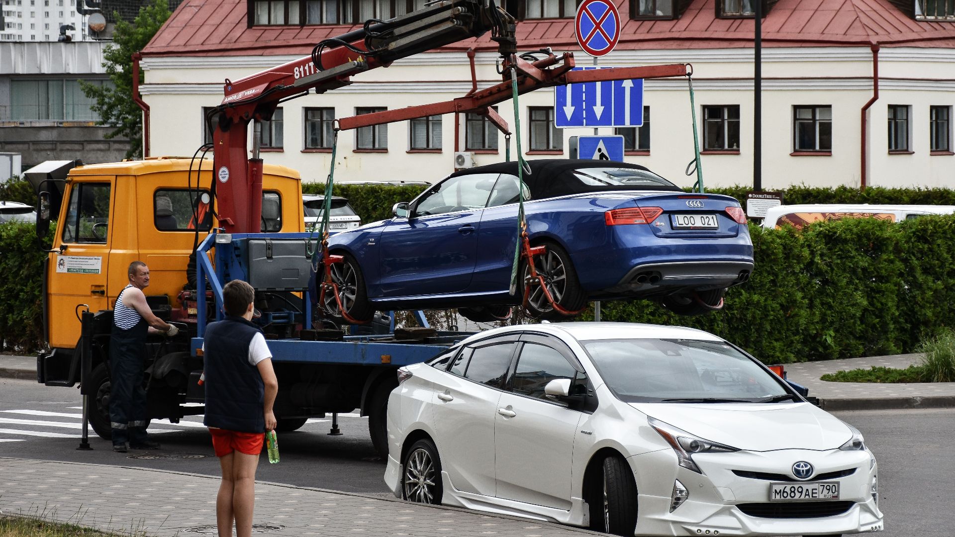 Towing a blue Audi convertible in a bustling city street.