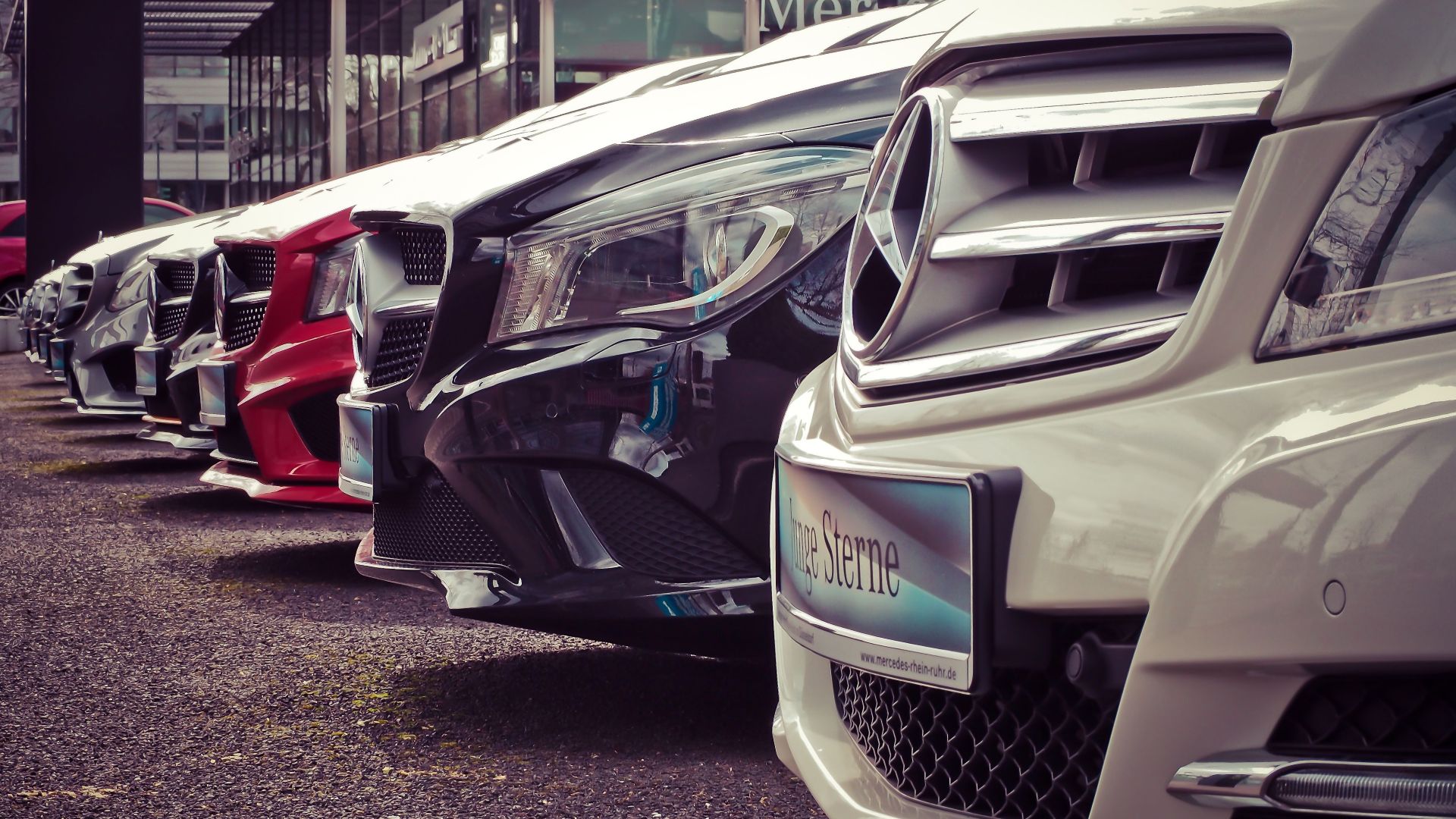 Luxury cars lined up at an outdoor dealership, showcasing sleek designs.