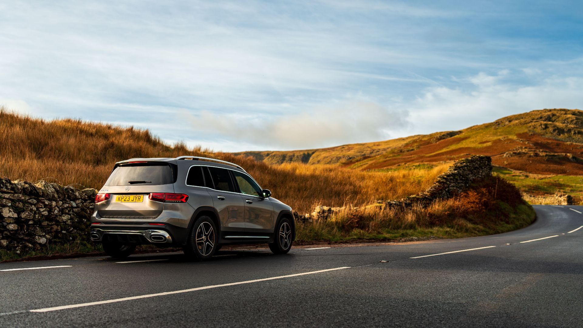 Sporty SUV navigating a winding road in a picturesque countryside setting under a clear blue sky.