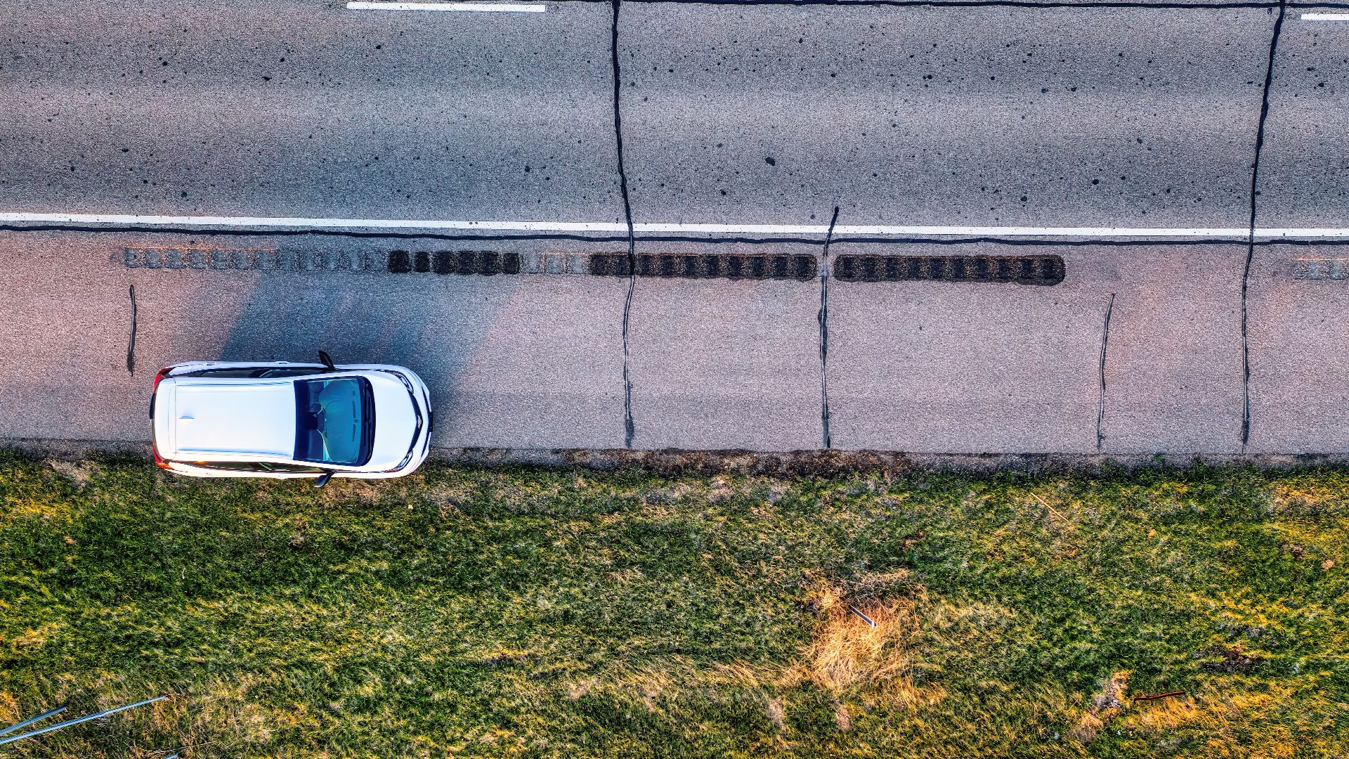 Drone shot of a white car parked on the roadside, surrounded by green grass, in Wabasha, MN.