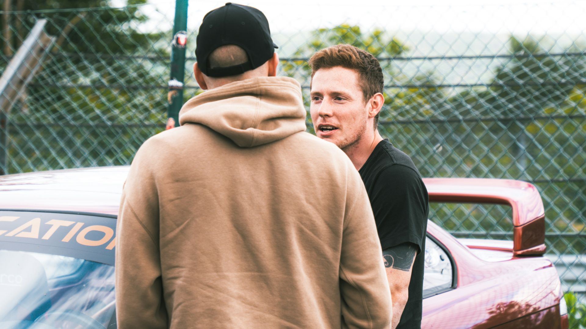 A group of men standing next to each other in front of a car