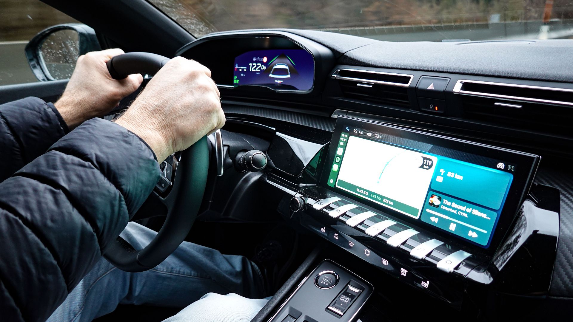 A detailed view of a car's interior with hands on the steering wheel, showcasing modern technology.