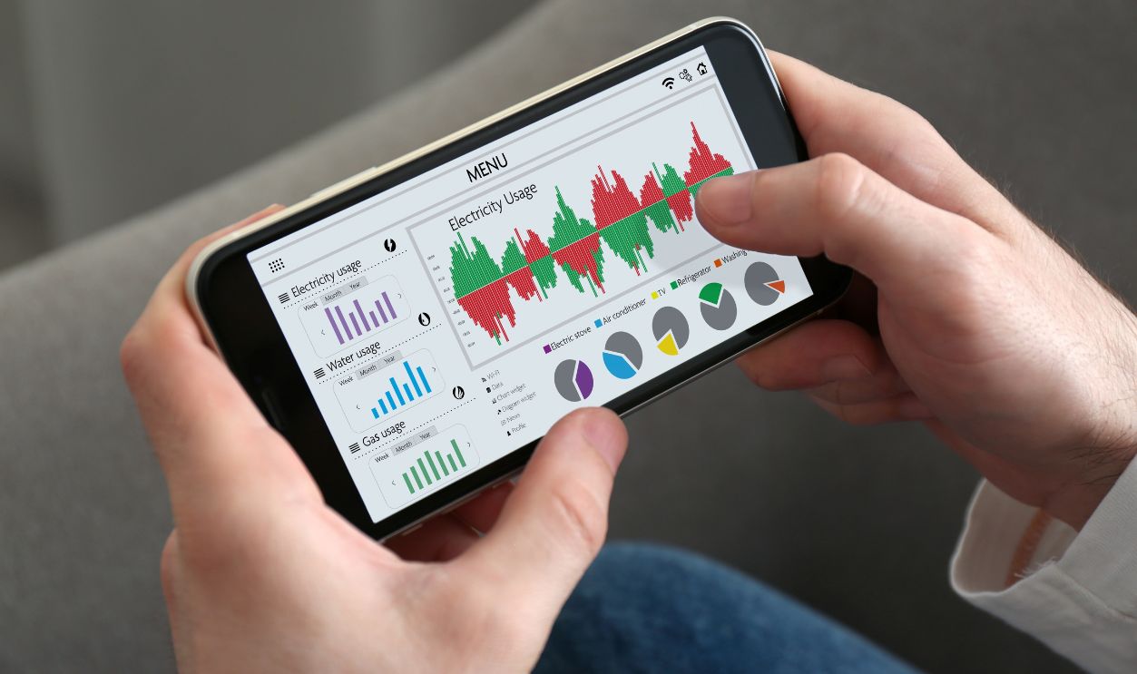 Man monitoring smart meter readings on mobile phone at home, closeup