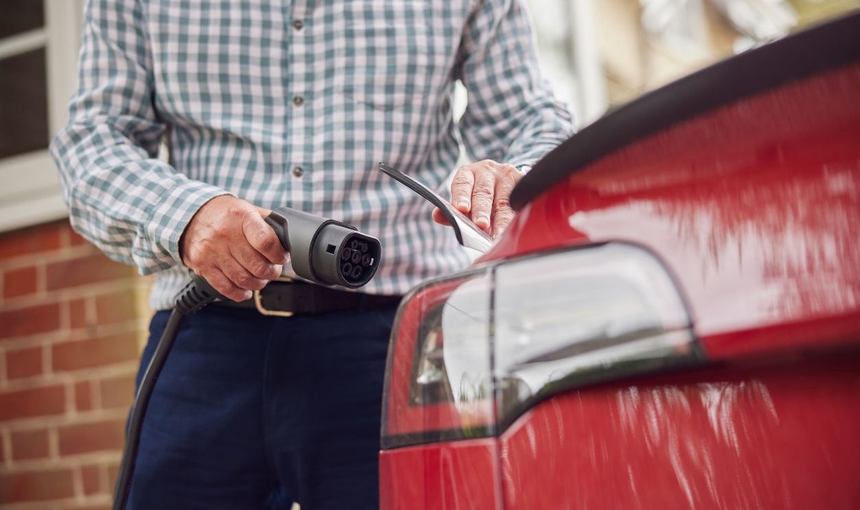 Close Up Of Man Attaching Charging Cable To Environmentally Friendly Zero Emission Electric Car At Home