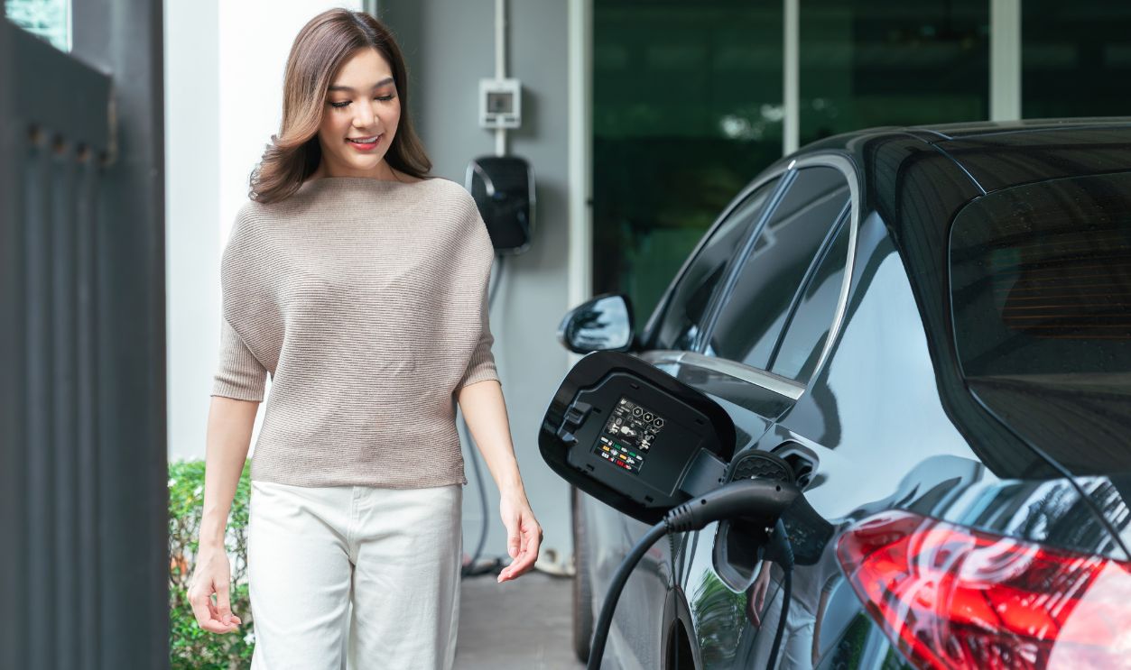 Female Driver Charging Electric Car at Home for Sustainable Transportation highlighting clean energy adoption and green lifestyle concept.