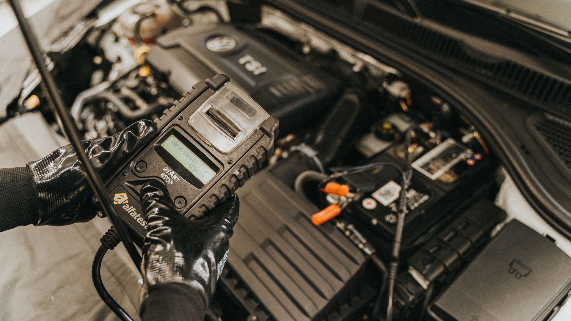 Mechanic diagnosing a car engine with a diagnostic tool, showcasing technical expertise and automotive care.