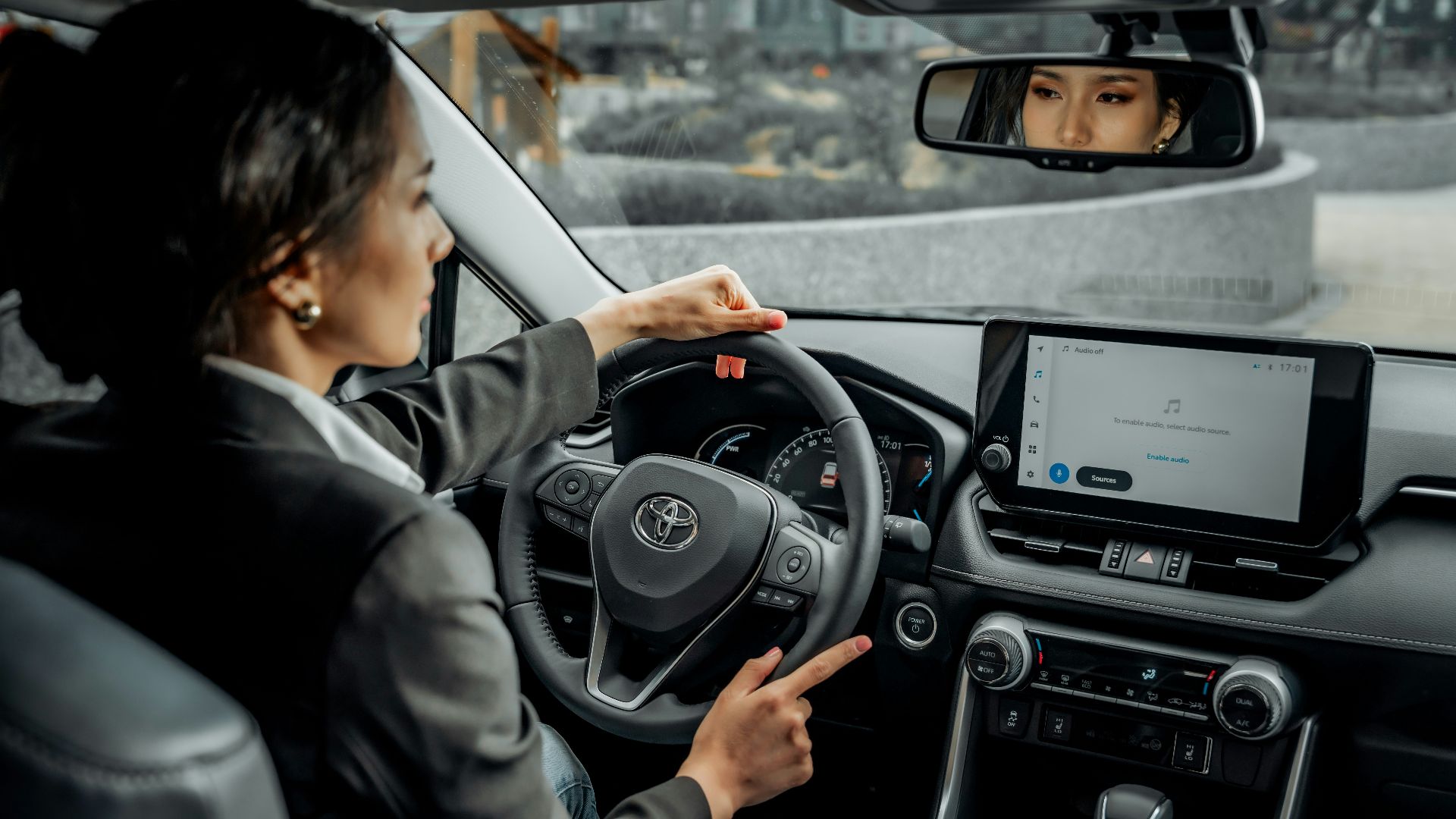 A woman driving a car with a man in the back seat