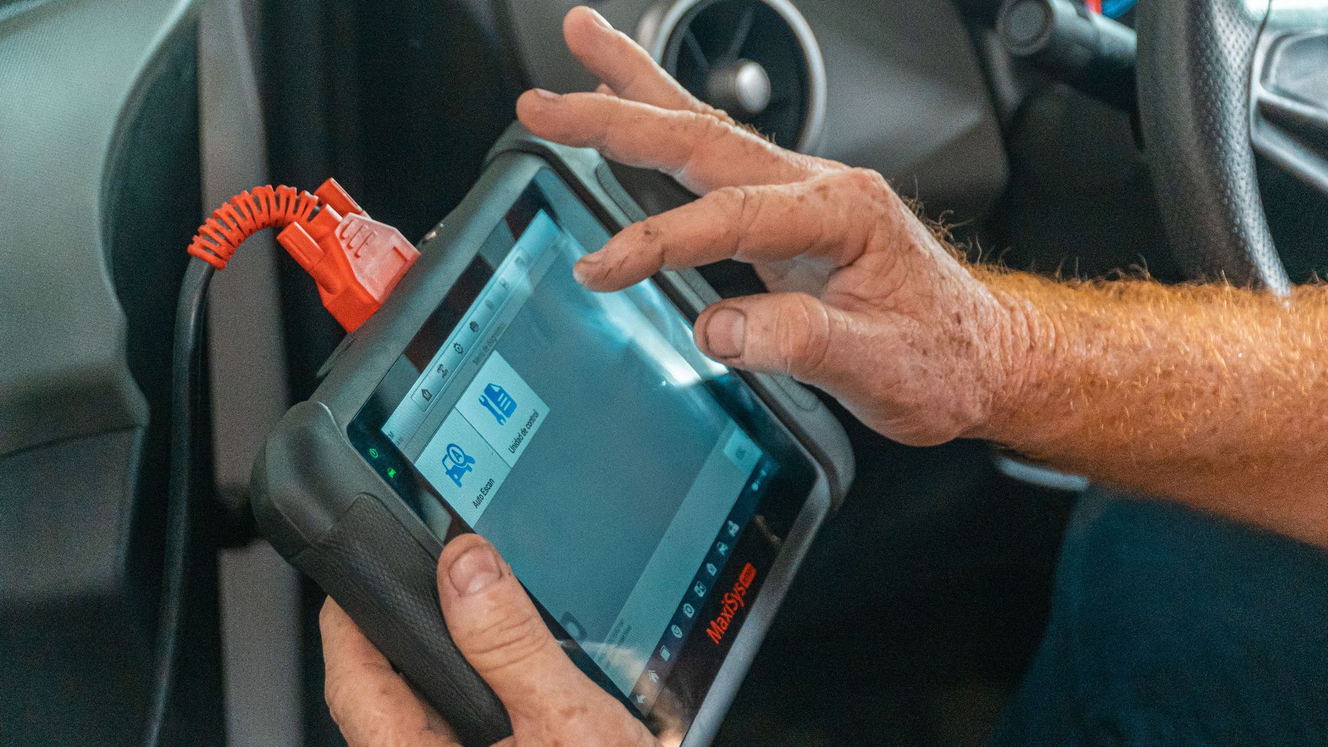 Mechanic using a diagnostic tool inside a car to check for engine issues and ensure proper maintenance.
