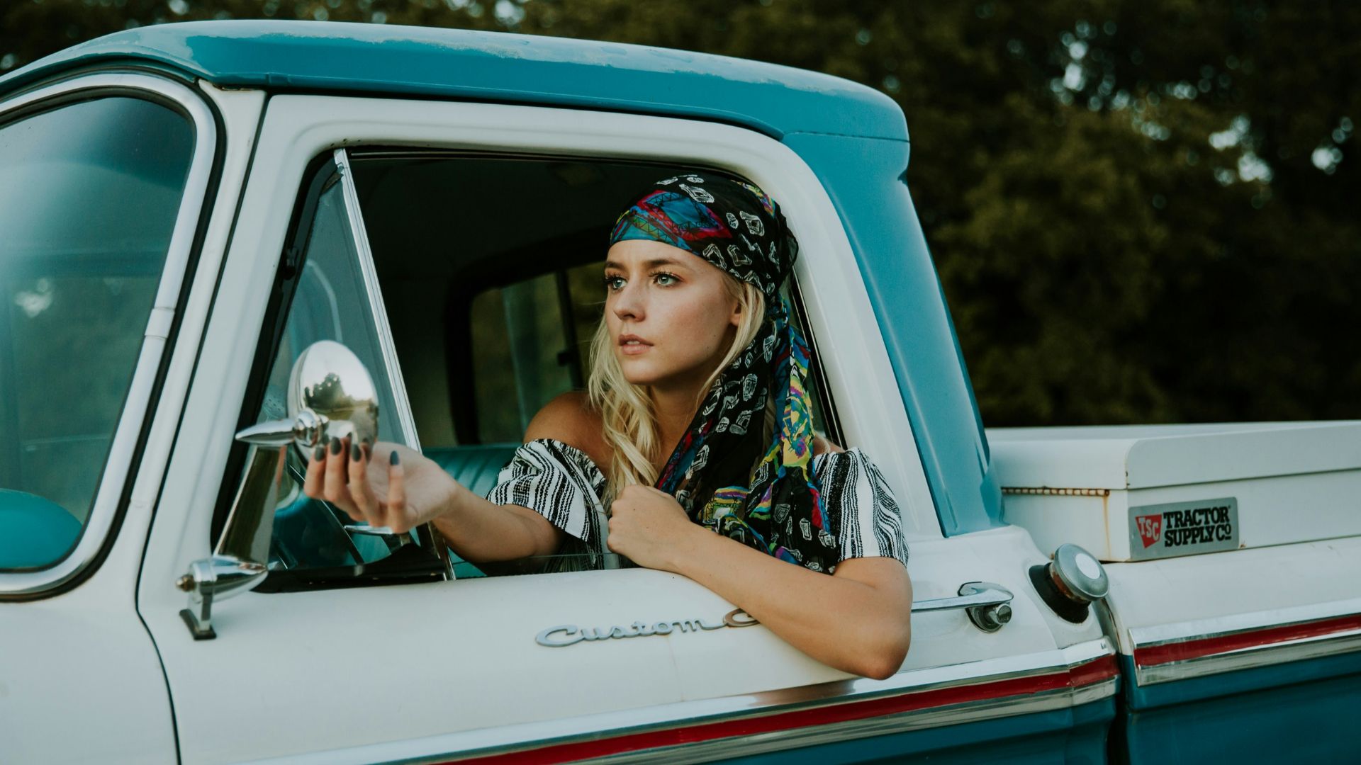 photography of woman holding side mirror in white and green 2-door pickup truck