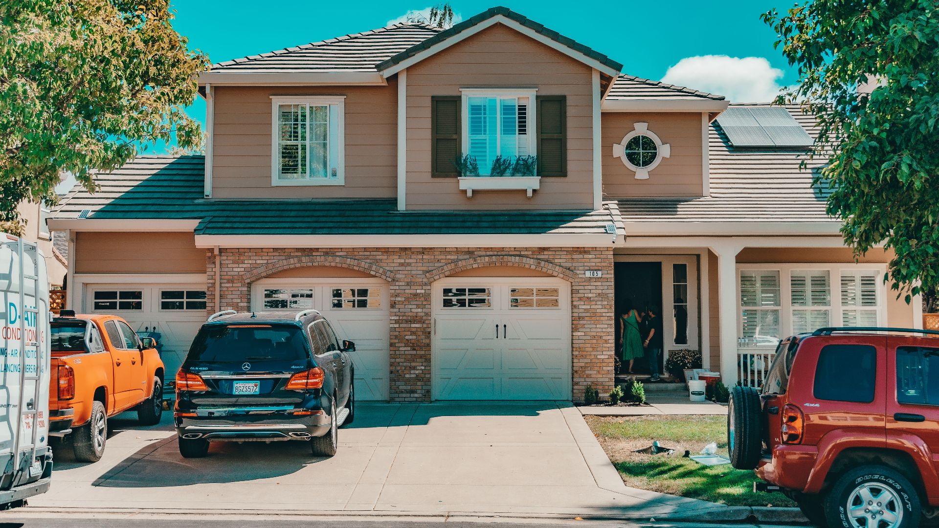 Charming suburban house with parked cars and vibrant summer setting.
