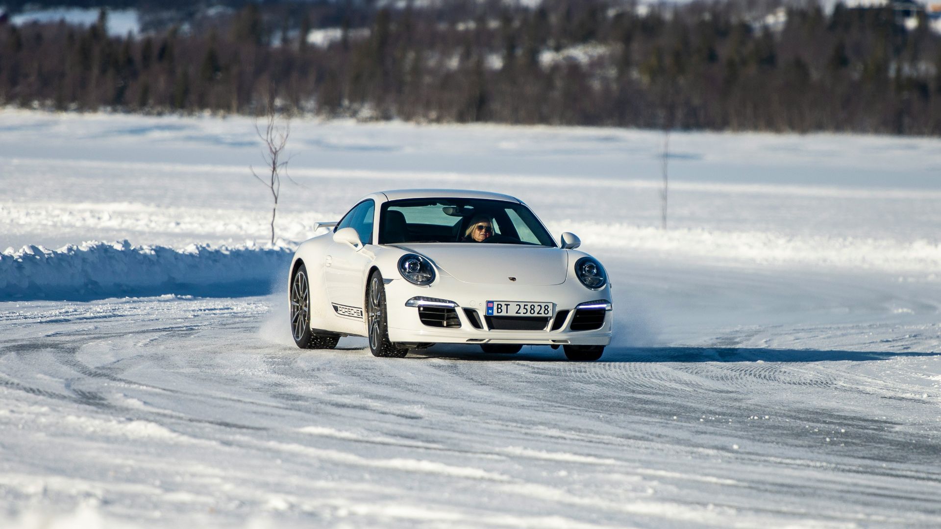 a white car driving down a snow covered road