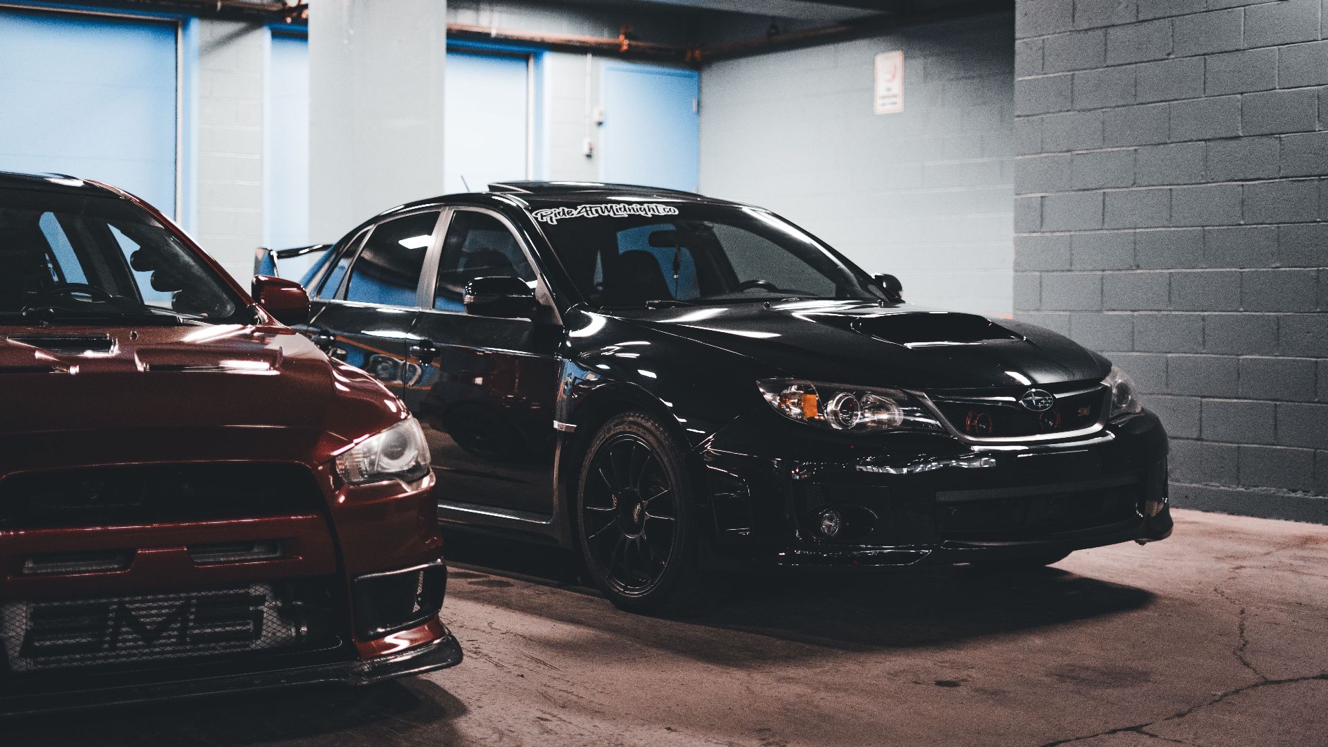 Two sports cars stylishly parked in an urban garage, showcasing modern automotive design.