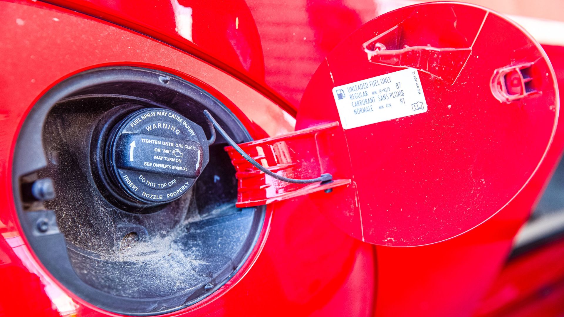 Detailed view of a red car's fuel cap and warning label. Ideal for automotive themes.