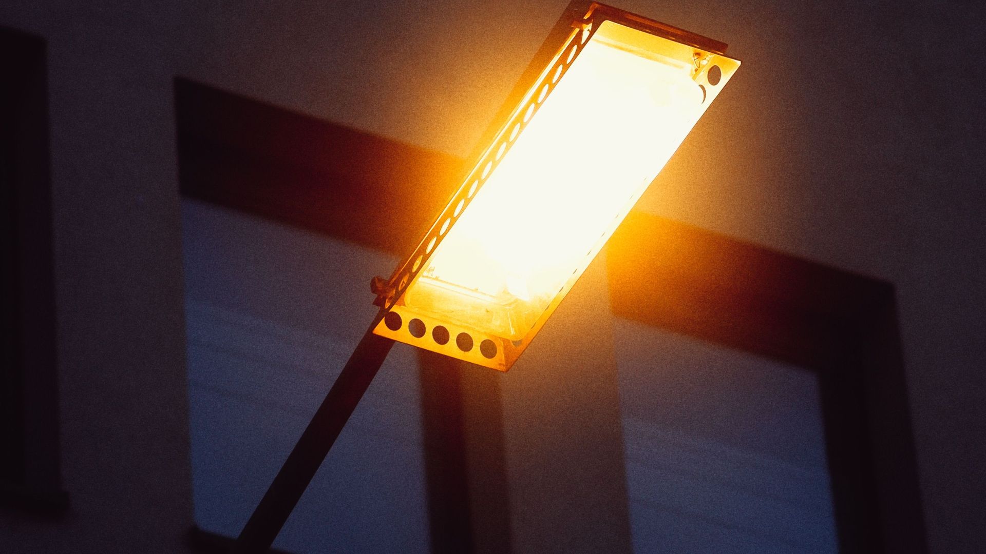 Close-up of a bright streetlight casting a warm glow against a building background.