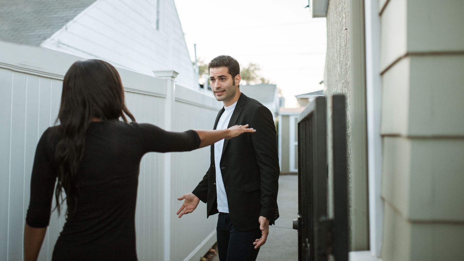 Man and woman having an argument in a suburban alleyway during the day.
