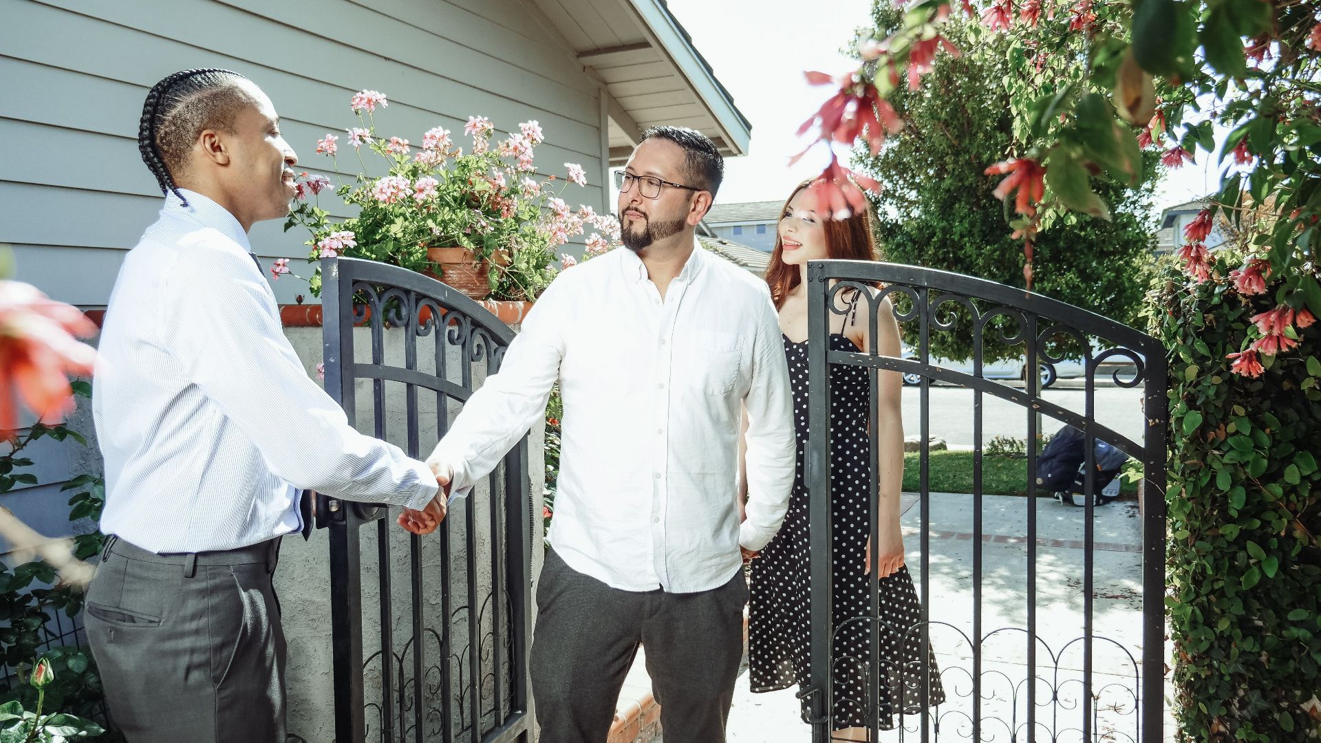 A real estate agent meets a couple at their new home, symbolizing a successful property transaction.