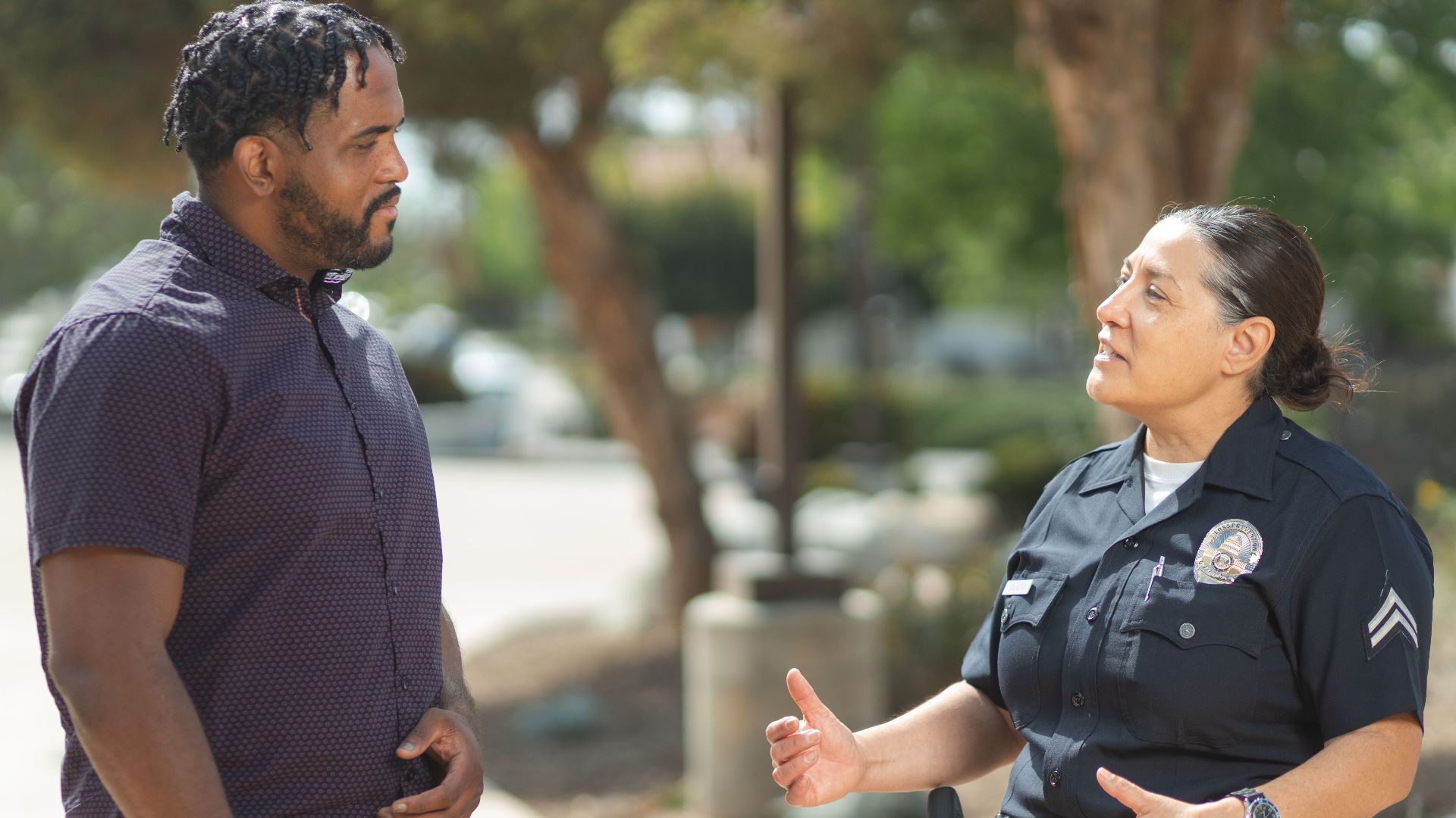 A police officer engaging warmly with a community member outdoors on a sunny day.