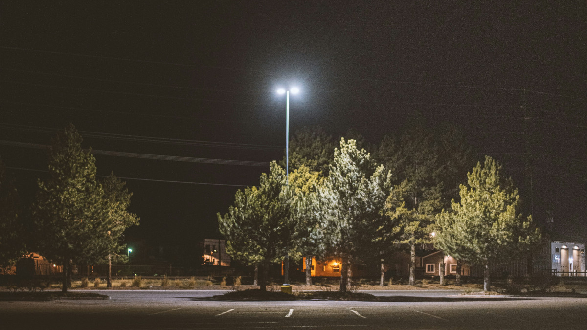 an empty parking lot at night with a street light in the background