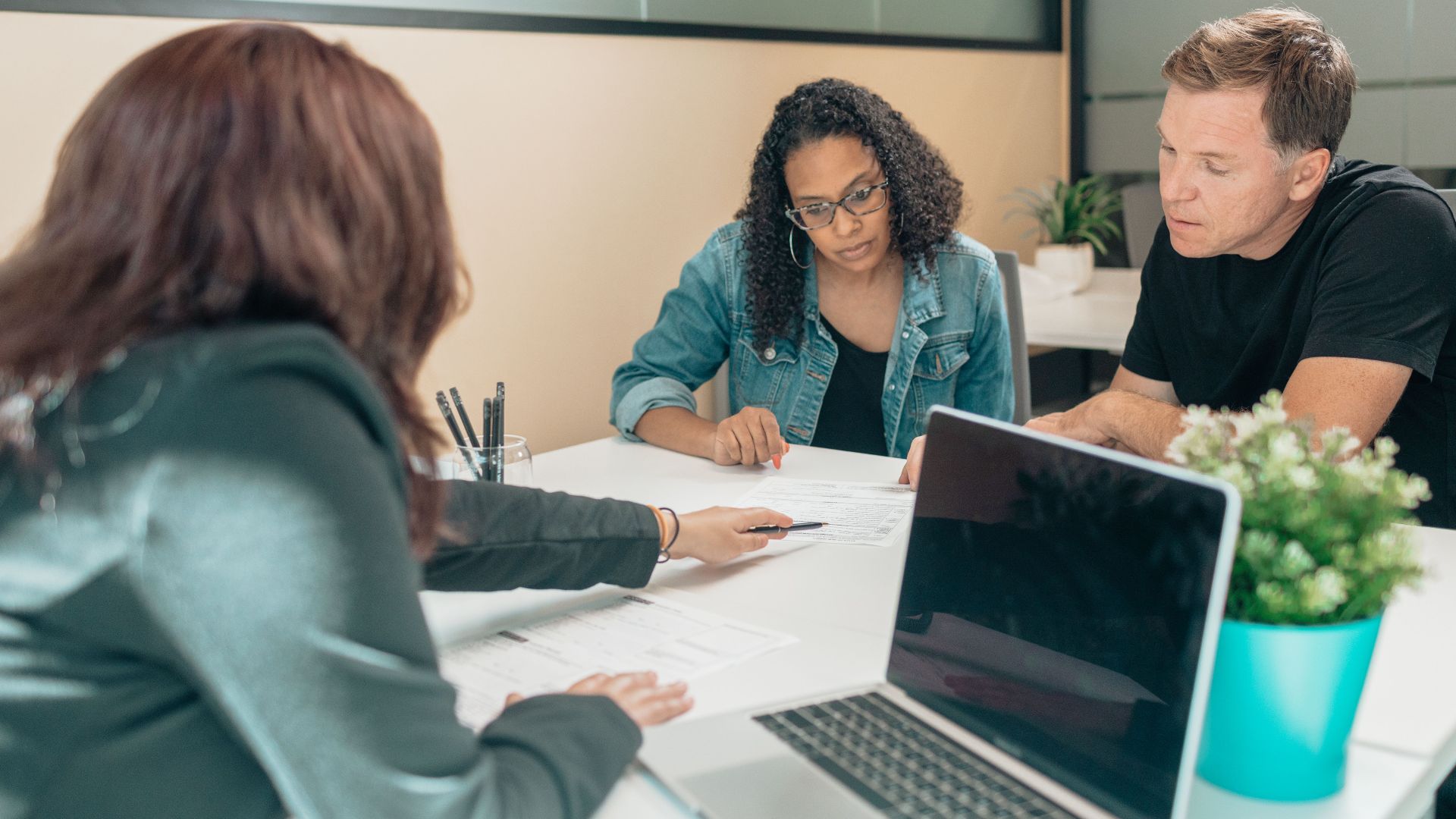 Couple meeting with advisor for adoption process in a modern office setting.