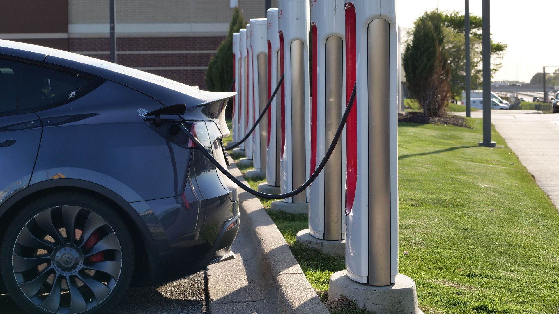 Electric car plugged into a row of charging stations, showcasing modern EV infrastructure.