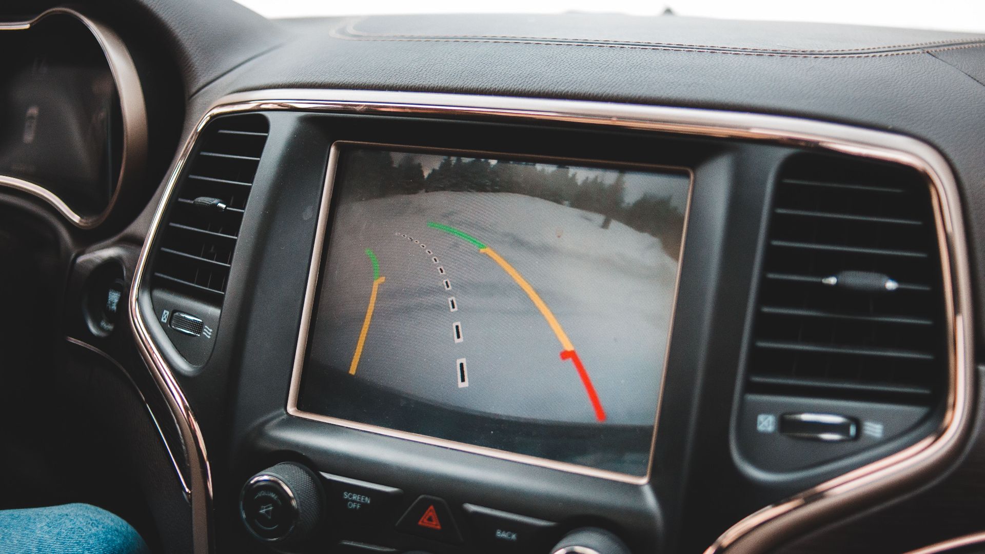 Close-up of a car's dashboard showing a rearview camera display for parking assistance.