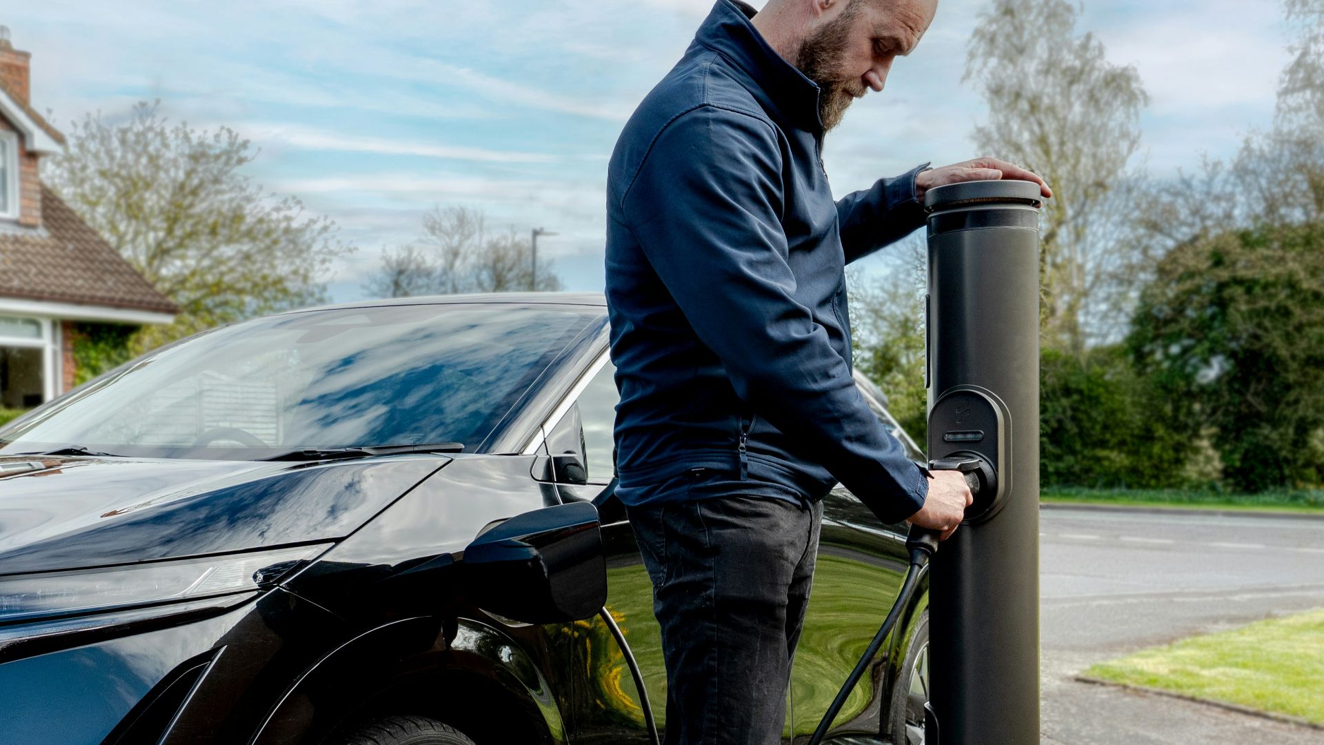 Man charging an electric car at an outdoor station