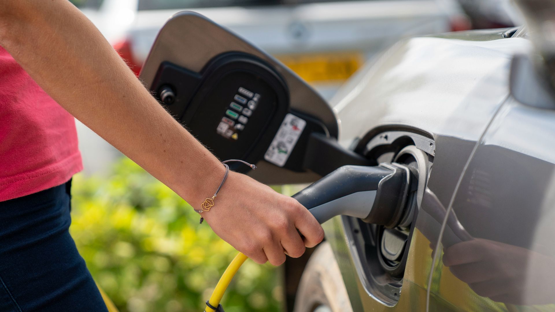 Person plugging electric car charger into vehicle