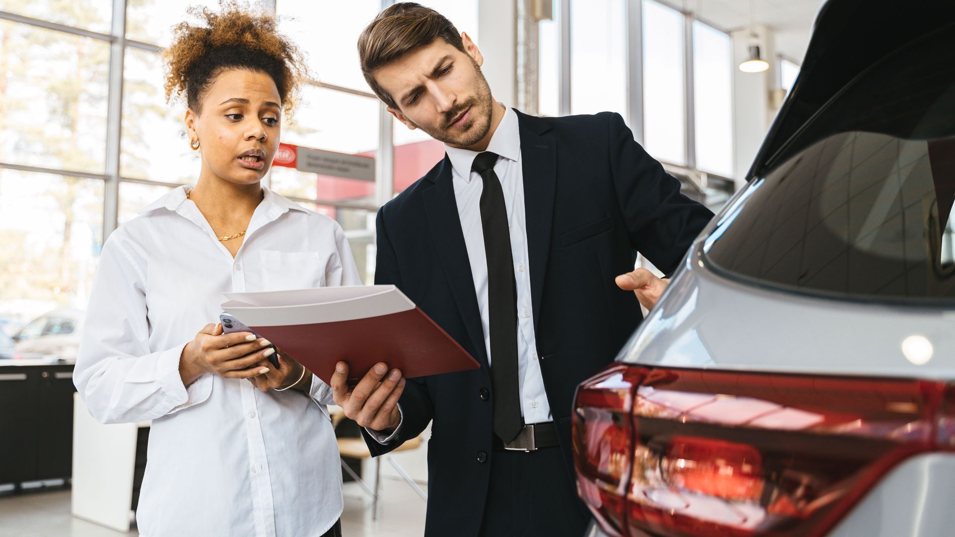 A professional consultation at a car dealership involving a sales agent and a customer discussing a vehicle purchase.