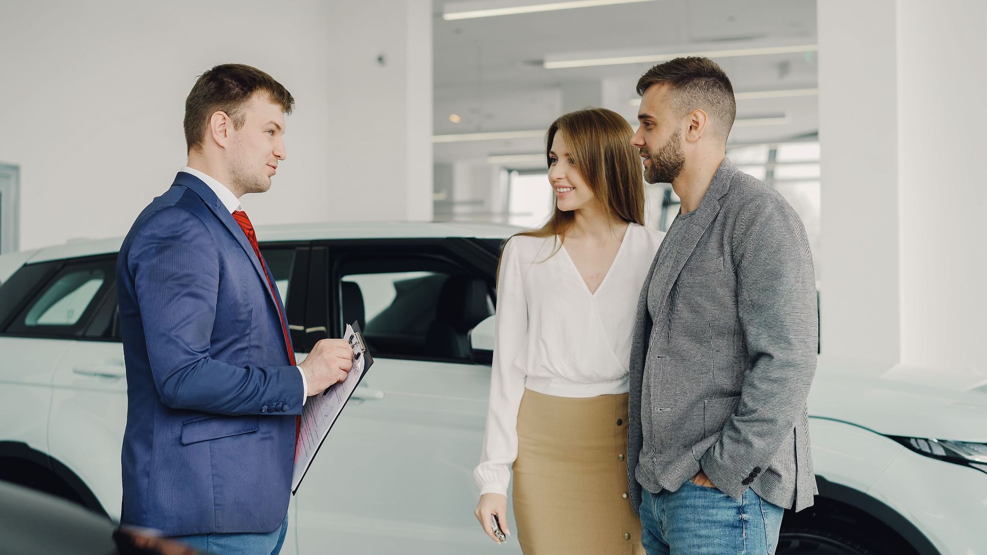 A couple discussing car purchase options with a salesperson in a modern showroom.