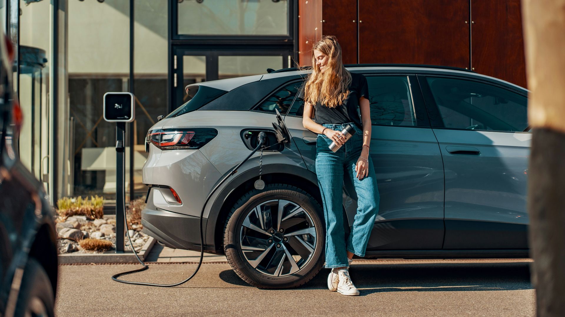 a woman standing next to a blue car