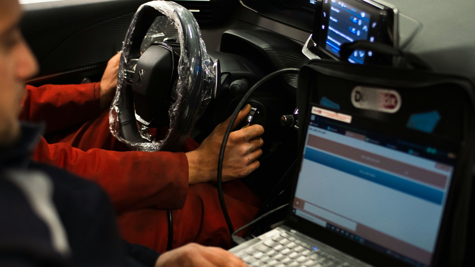 A man sitting in a car using a laptop computer