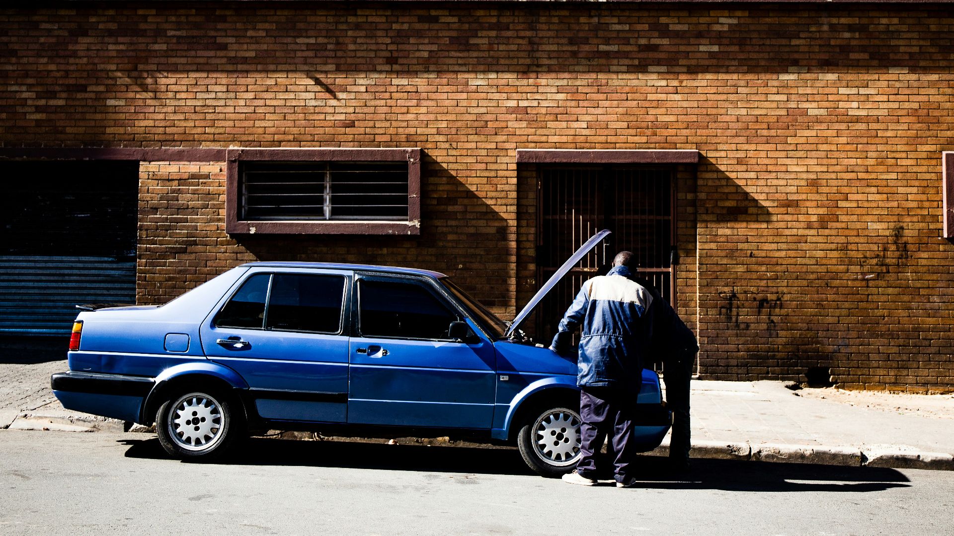 two men fixing up blue car