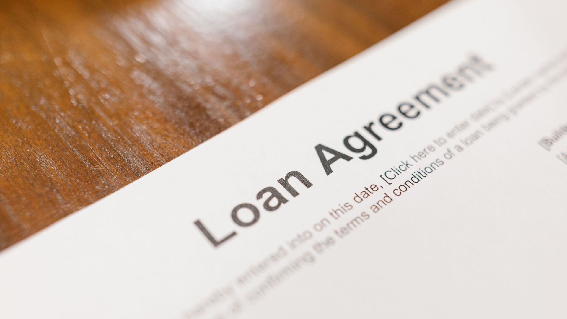 Detailed loan agreement document close-up on a wooden table representing legal and financial concepts.