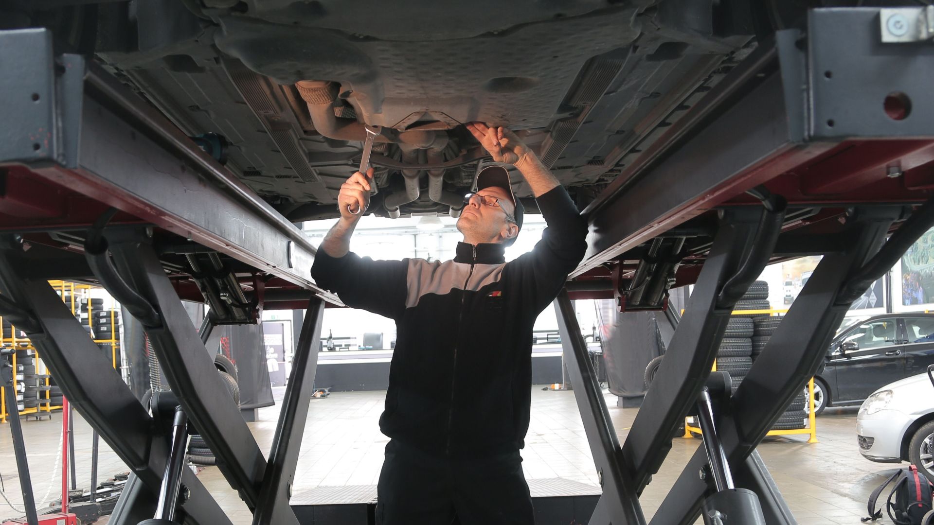 Mechanic inspecting and repairing a vehicle in a professional auto garage.