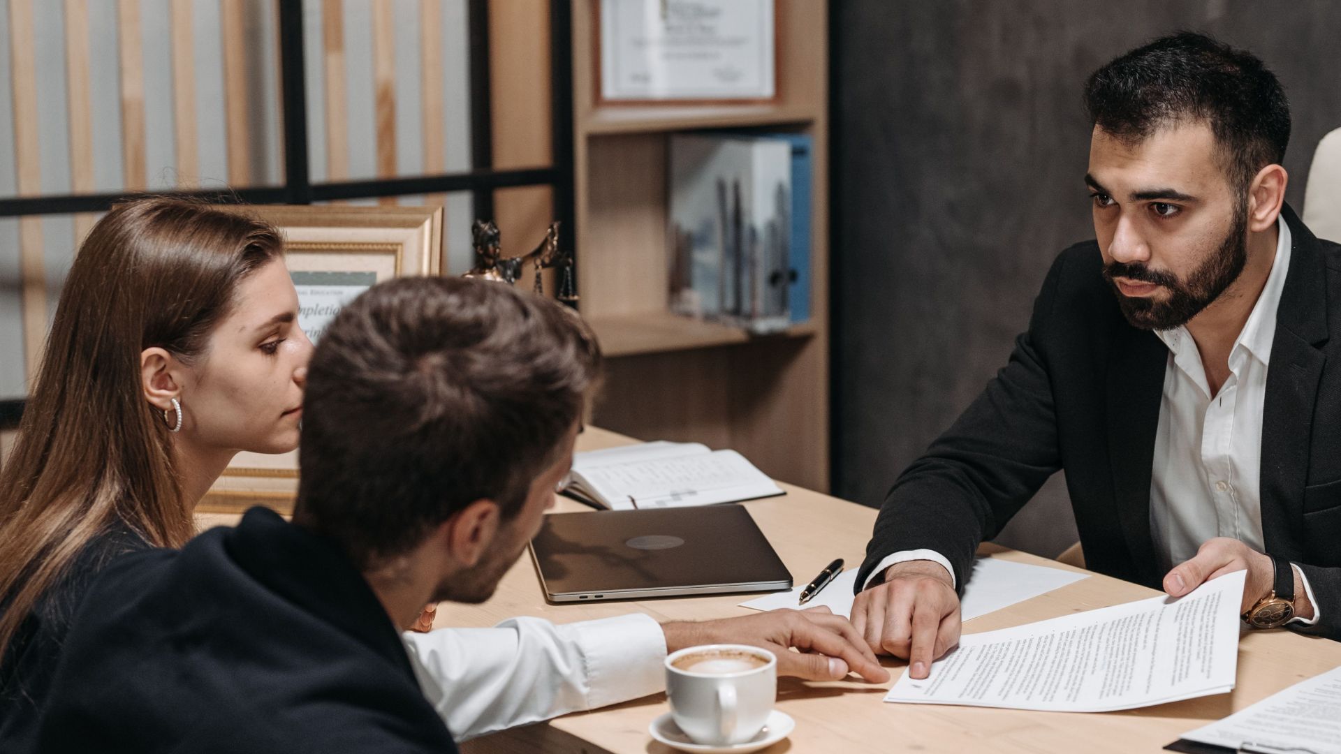 Lawyer discussing legal documents with clients at office desk.
