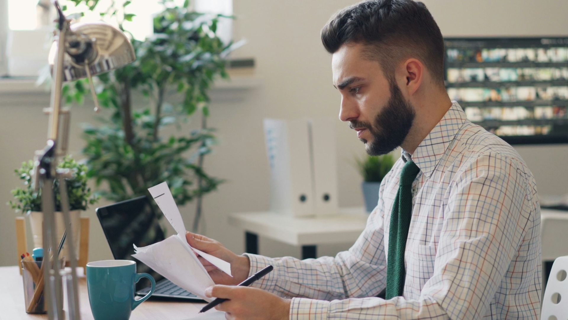 a man sitting at a desk with a laptop and papers