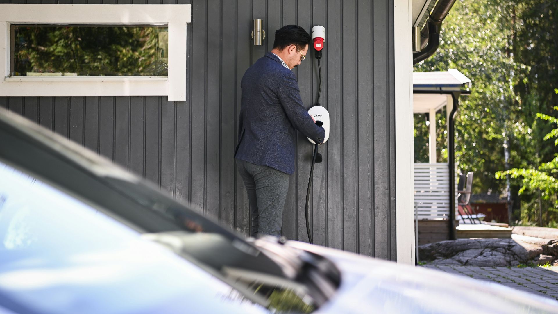Man plugs in an electric vehicle charging cable