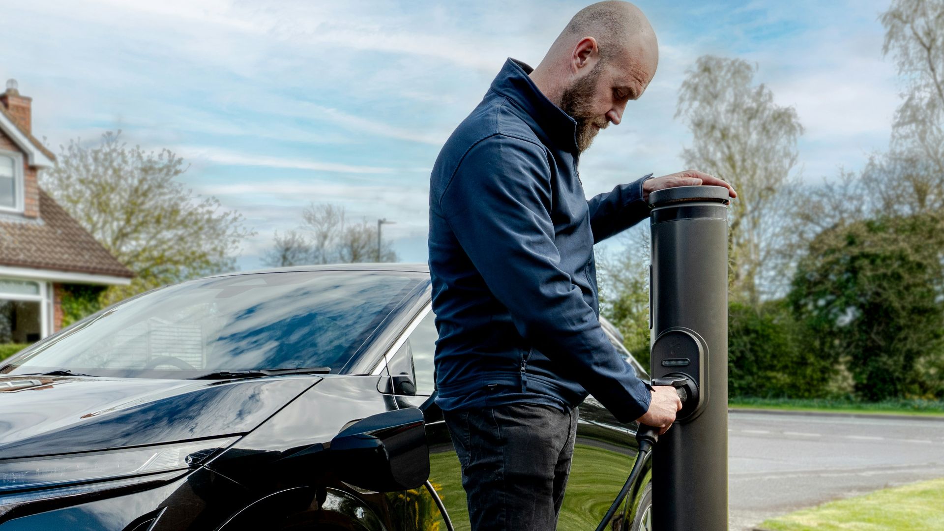 Man charging an electric car at an outdoor station
