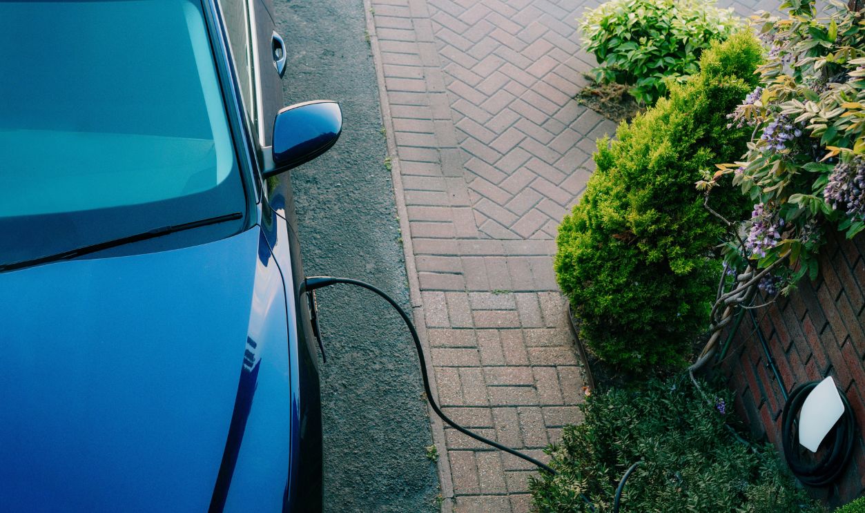 Top view electric car plugged into a charging station while parked in home. Residential EV Charging Station. Home EV Charging. Sustainable Power of a Wall-Mounted Charger. Future of Clean Transport