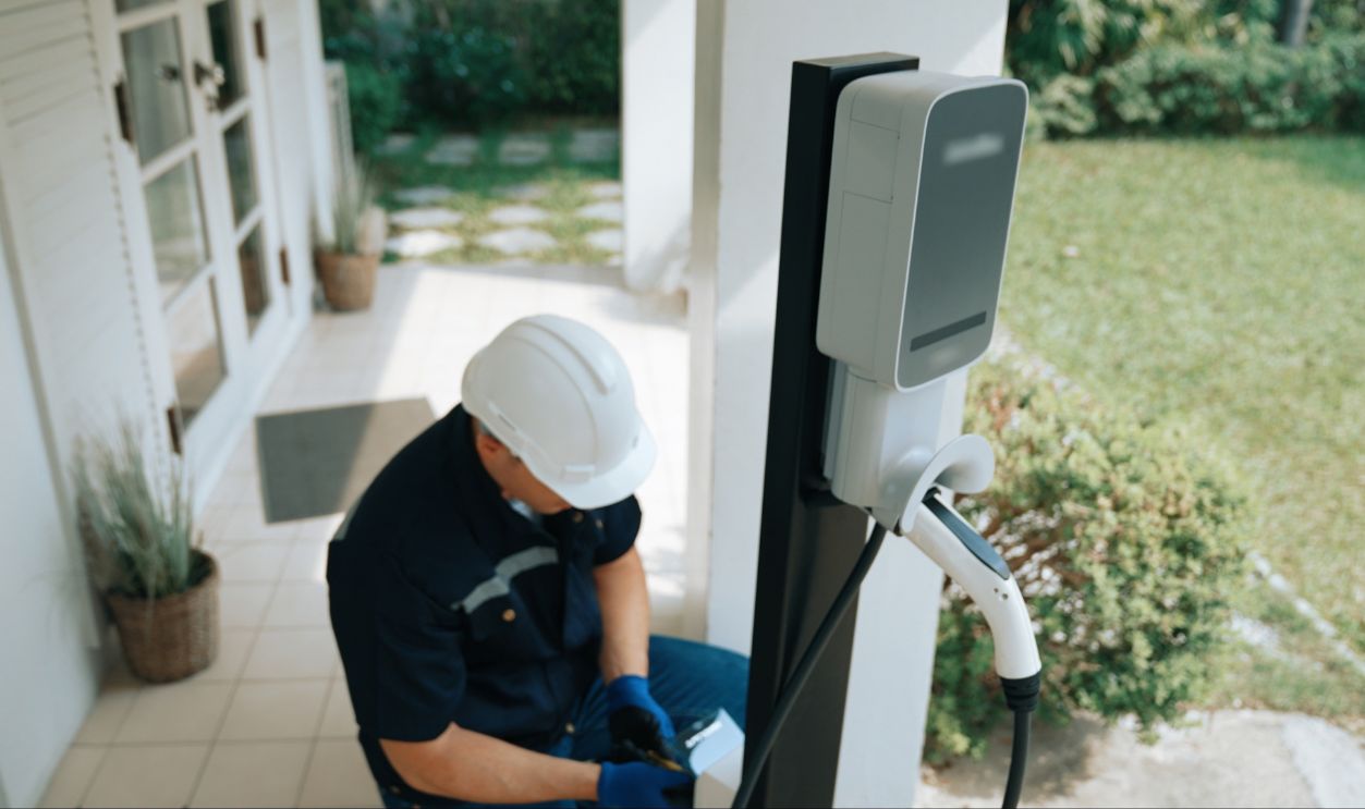Qualified technician install home EV charging station, providing maintenance service for electric vehicle's battery charging platform at home. EV car technology for residential utilization. Synchronos
