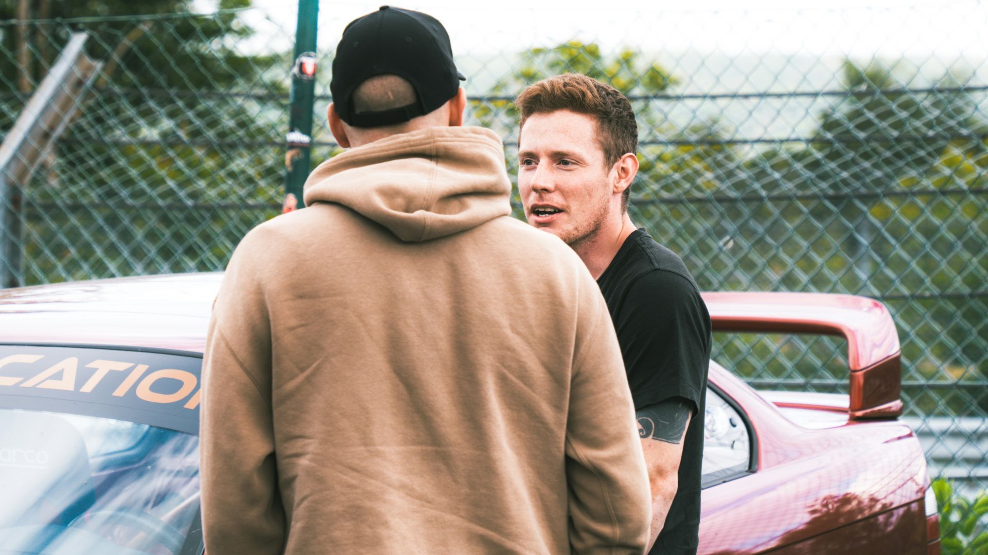 A group of men standing next to each other in front of a car