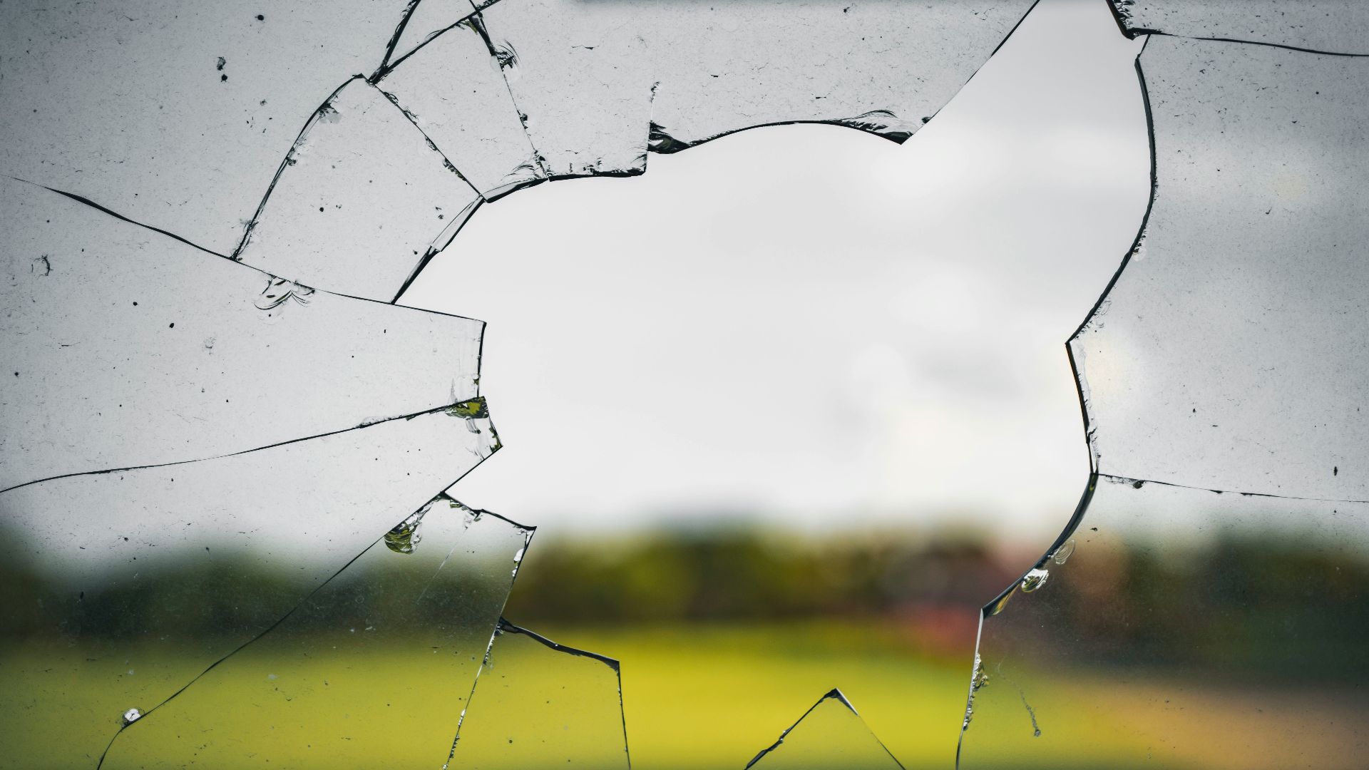 a broken glass window with a field in the background
