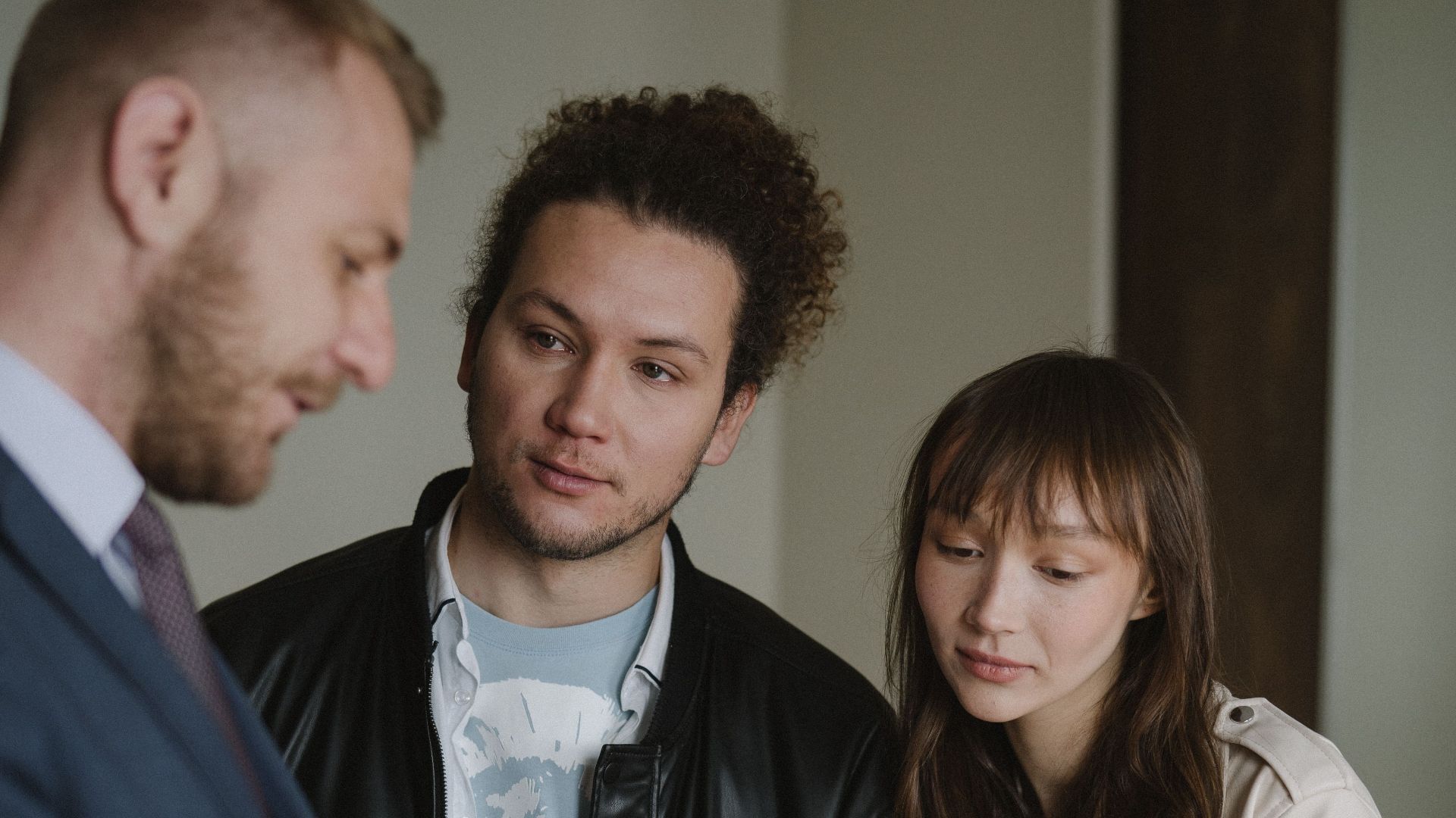 A real estate agent conversing with a potential client couple inside a modern home.