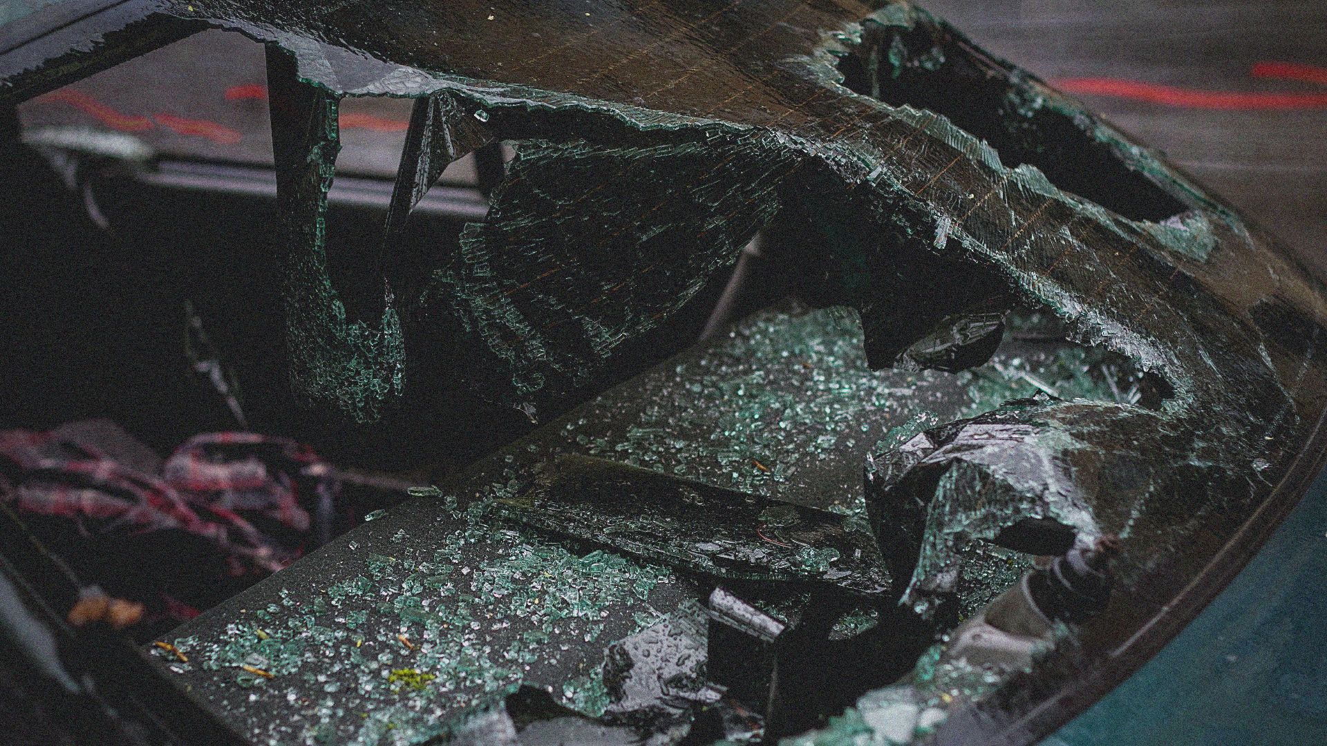 Detailed view of shattered car windshield after accident, emphasizing damage and broken glass.