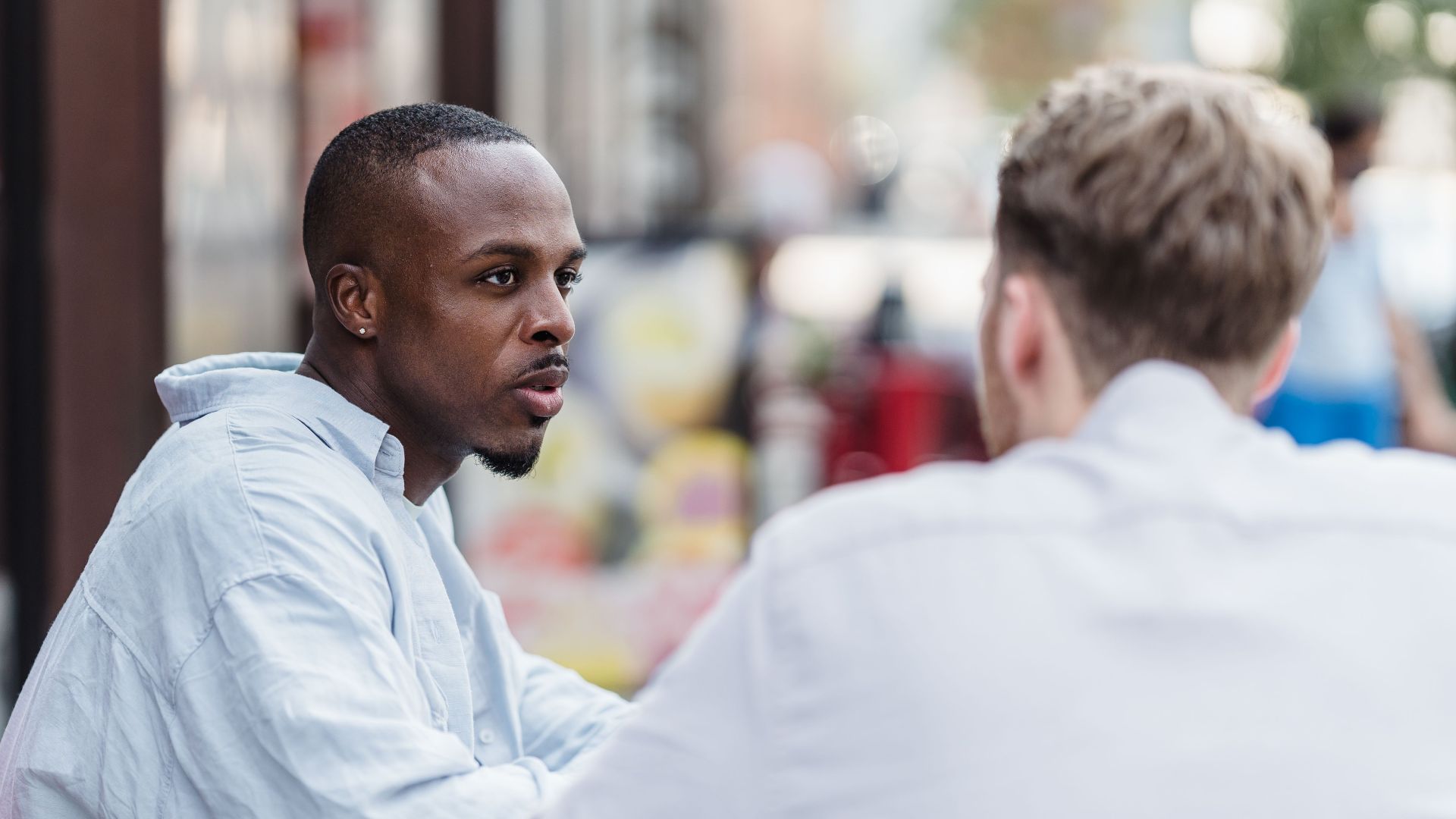 Two men having a conversation in an outdoor setting on a sunny day.