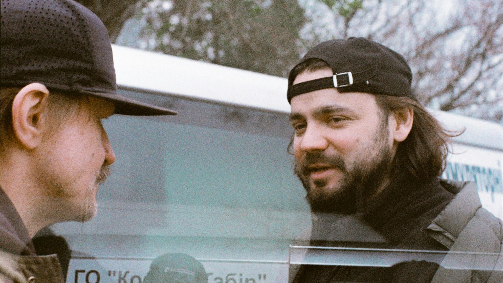 Two men talking near a bus with text