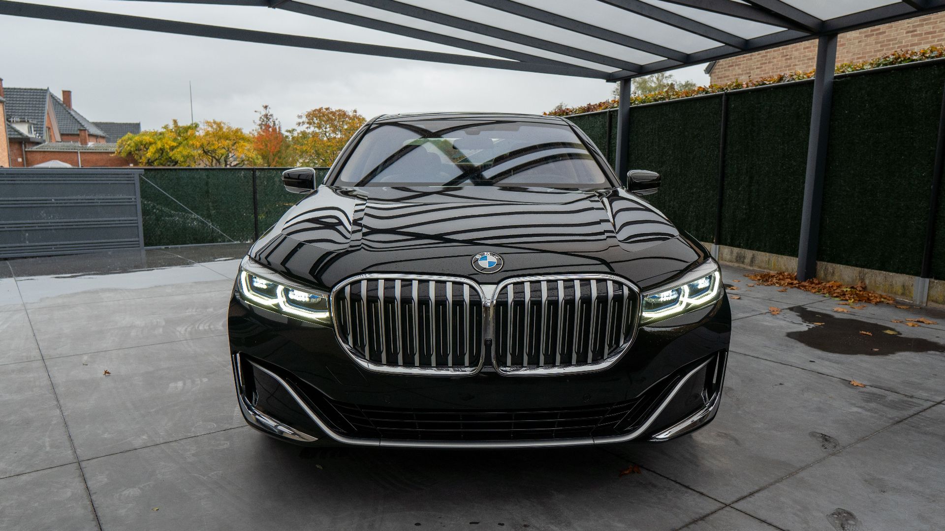 Front view of a shiny black luxury car parked in a modern covered garage setting.