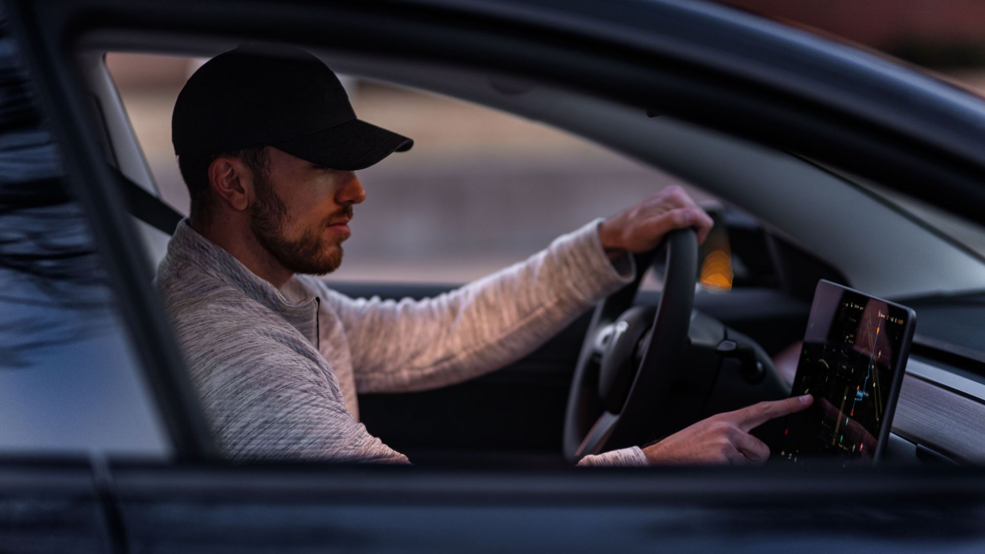 A man interacts with a touchscreen inside an electric car, driving through Dallas, TX.