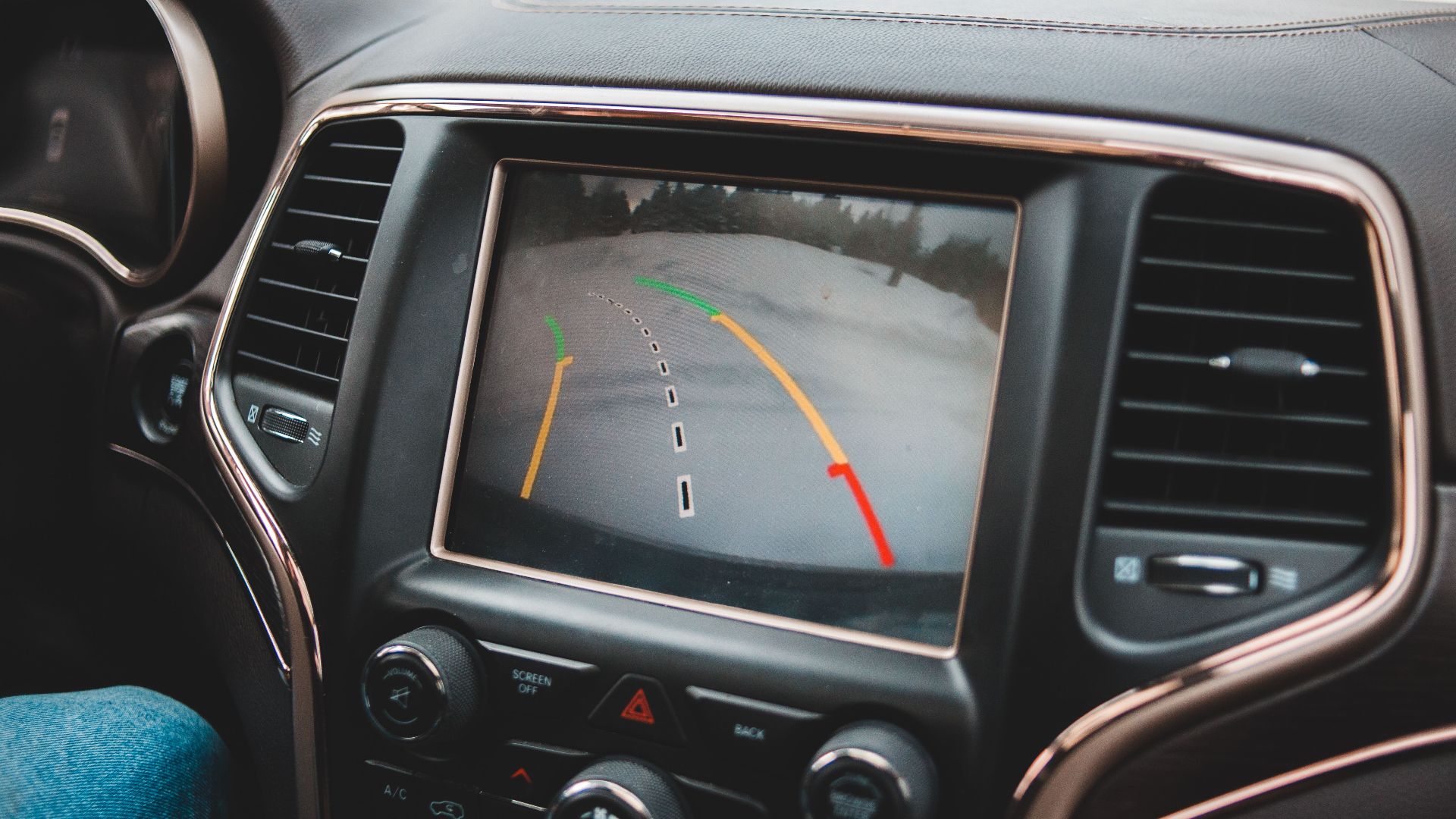 Close-up of a car's dashboard showing a rearview camera display for parking assistance.