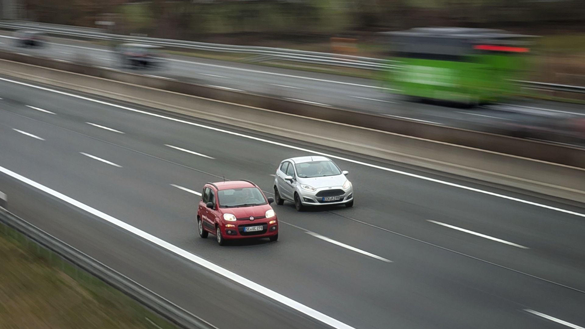 Two cars moving fast on a highway, showcasing speed and travel in motion.